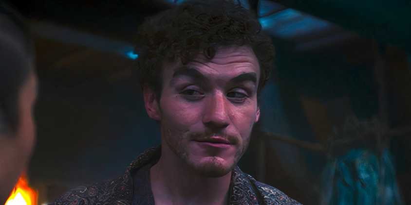 Mat looking off to the side and smiling at Min in The Wheel of Time season 3 episode 5
