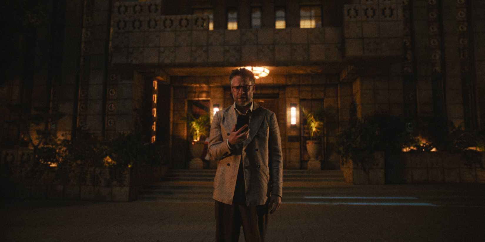 Matt outside the Continental Studios building holding his phone and looking stricken in The Studio