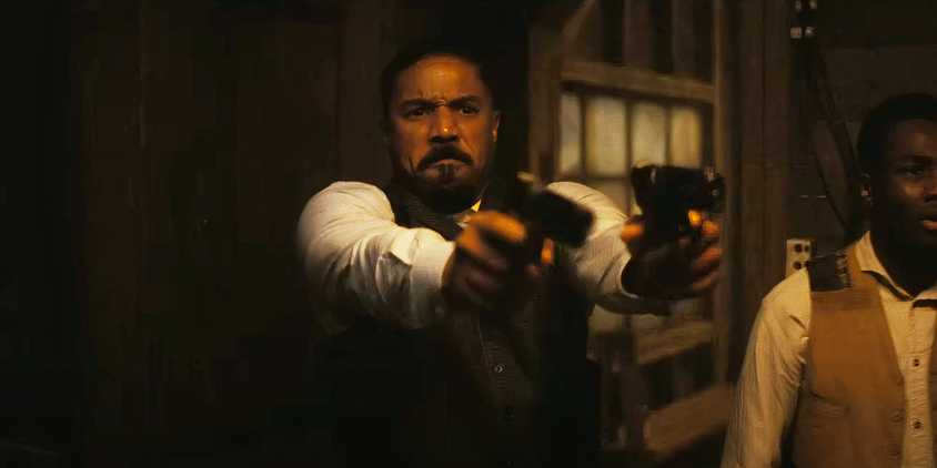 Michael B Jordan shooting two pistols in Sinners