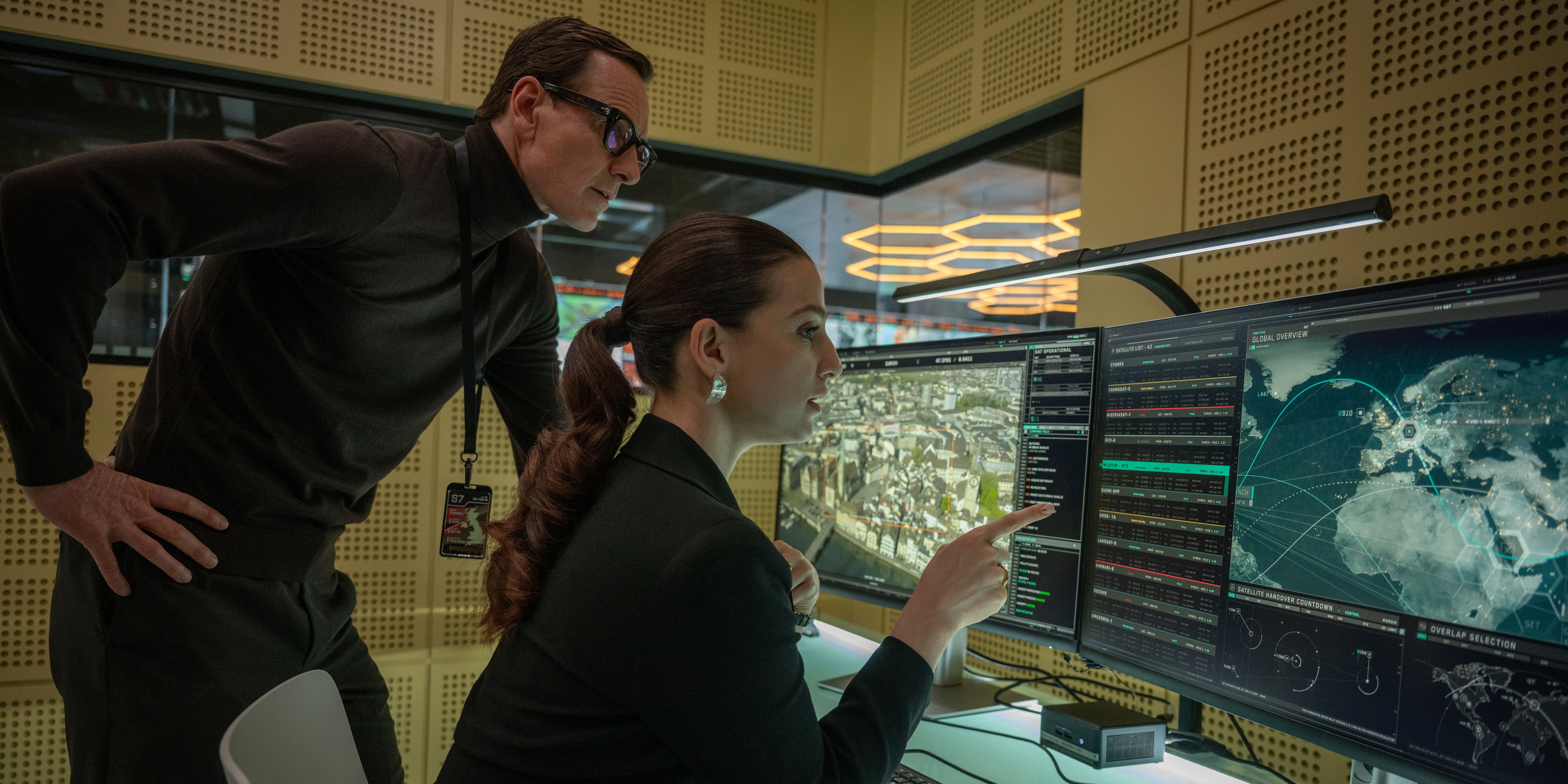 Michael Fᴀssbender looks at a computer with Marisa Abela in Black Bag