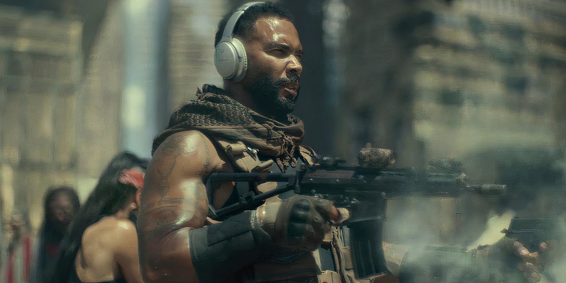 Omari Hardwick is using earphones and holds a gun. 