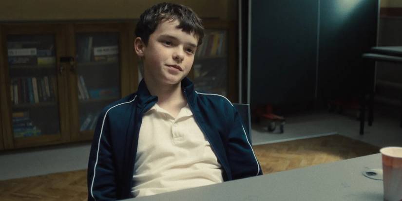 Owen Cooper as Jamie Miller sitting at a table in Adolescence