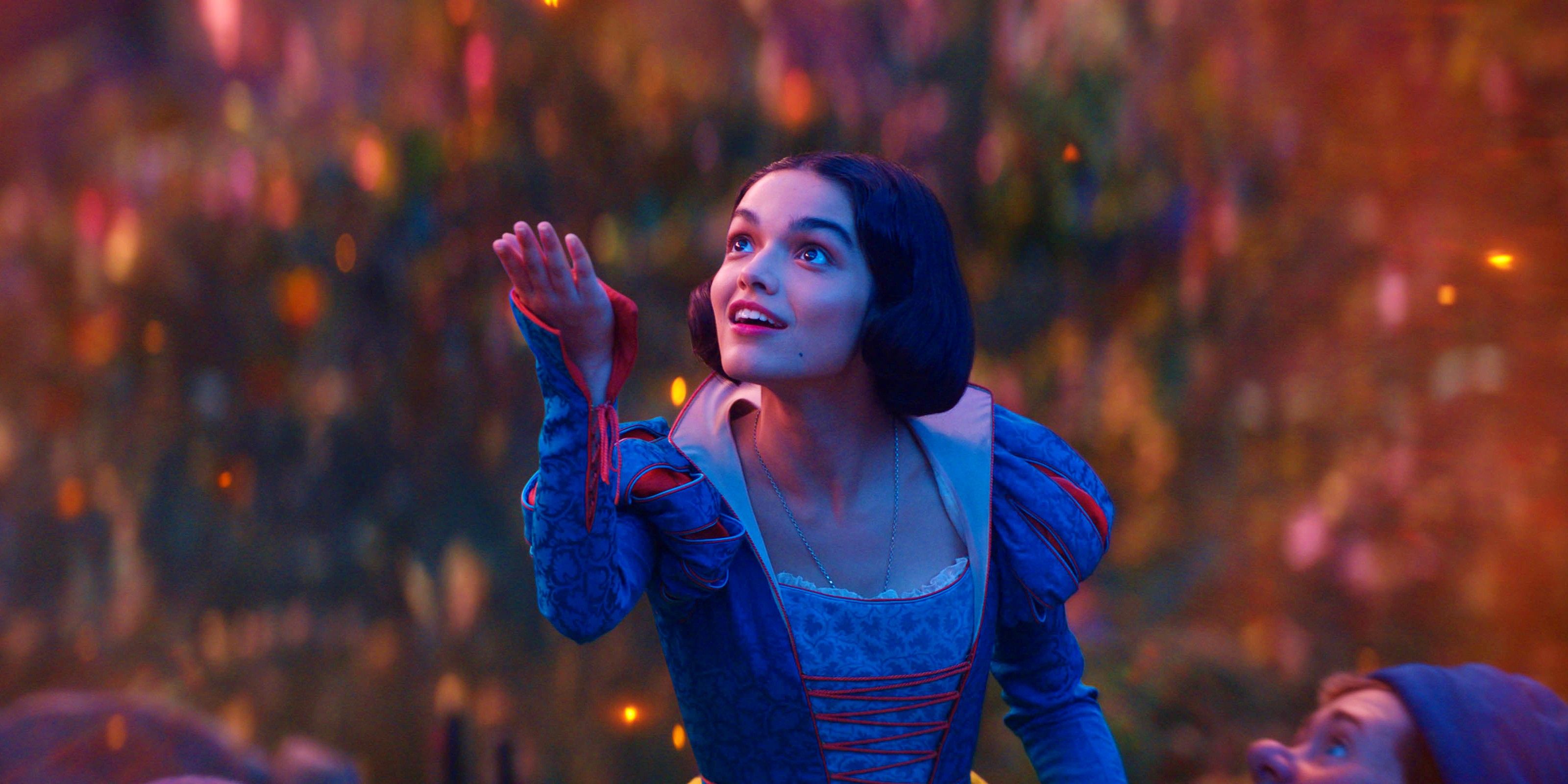 Rachel Zegler holding her hand up to catch a firefly with a look of wonder in Snow White