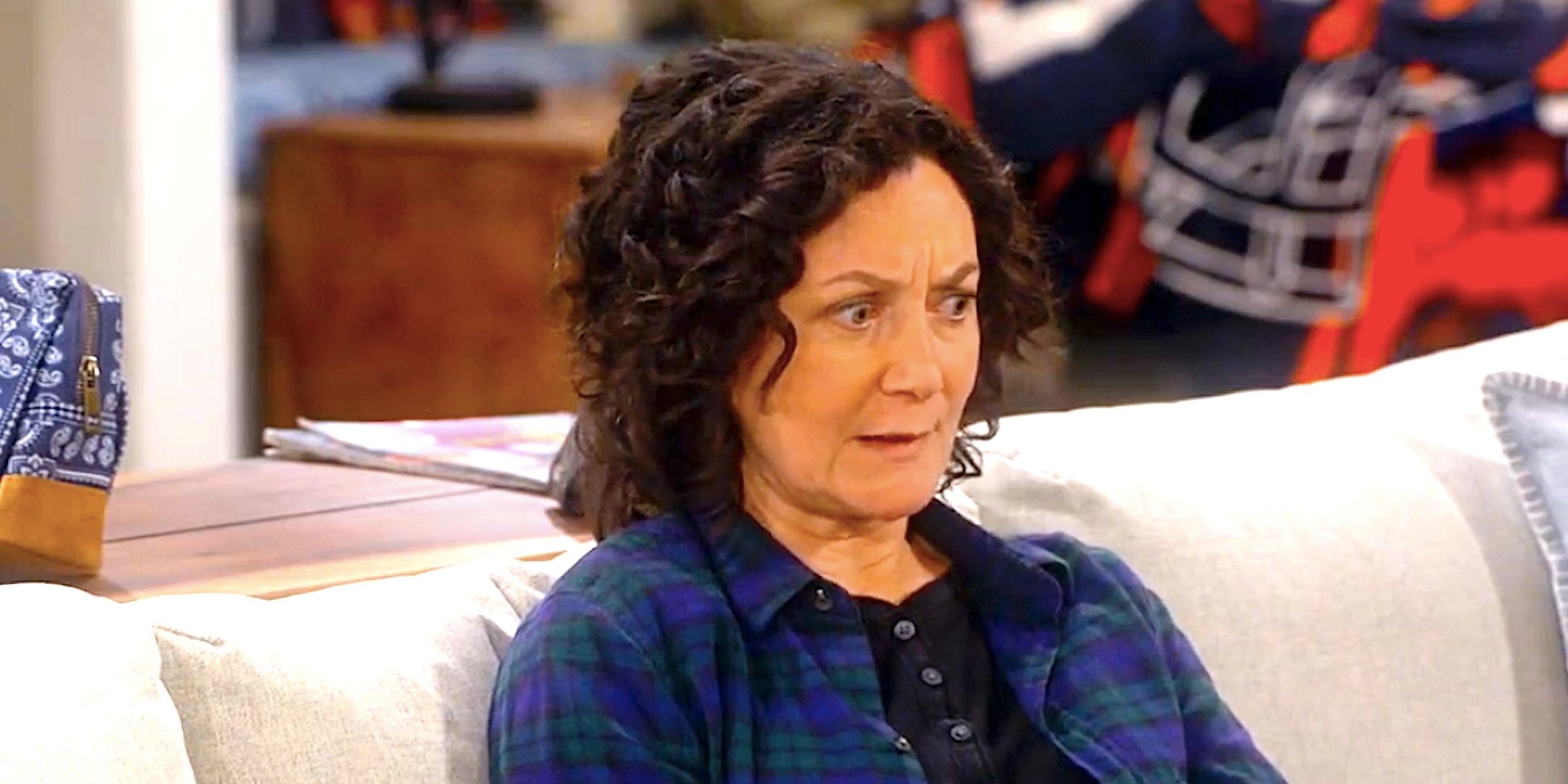 Sara Gilbert&rsquo;s Darlene looks worried sitting on a couch in The Conners season 7 episode 1