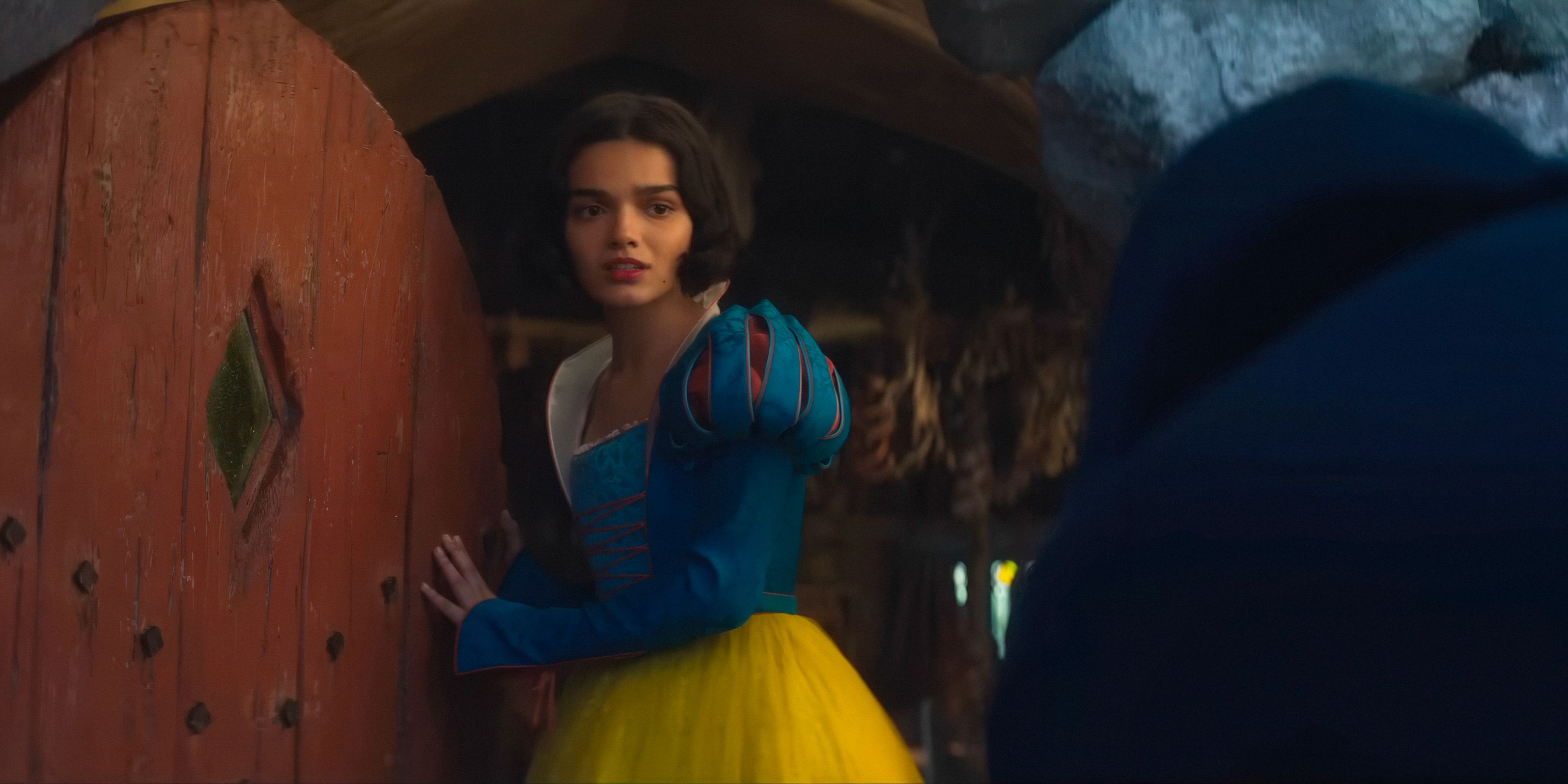 Snow White (Rachel Zegler), frightened, opens the cabin door to the Evil Queen in Snow White (2025)