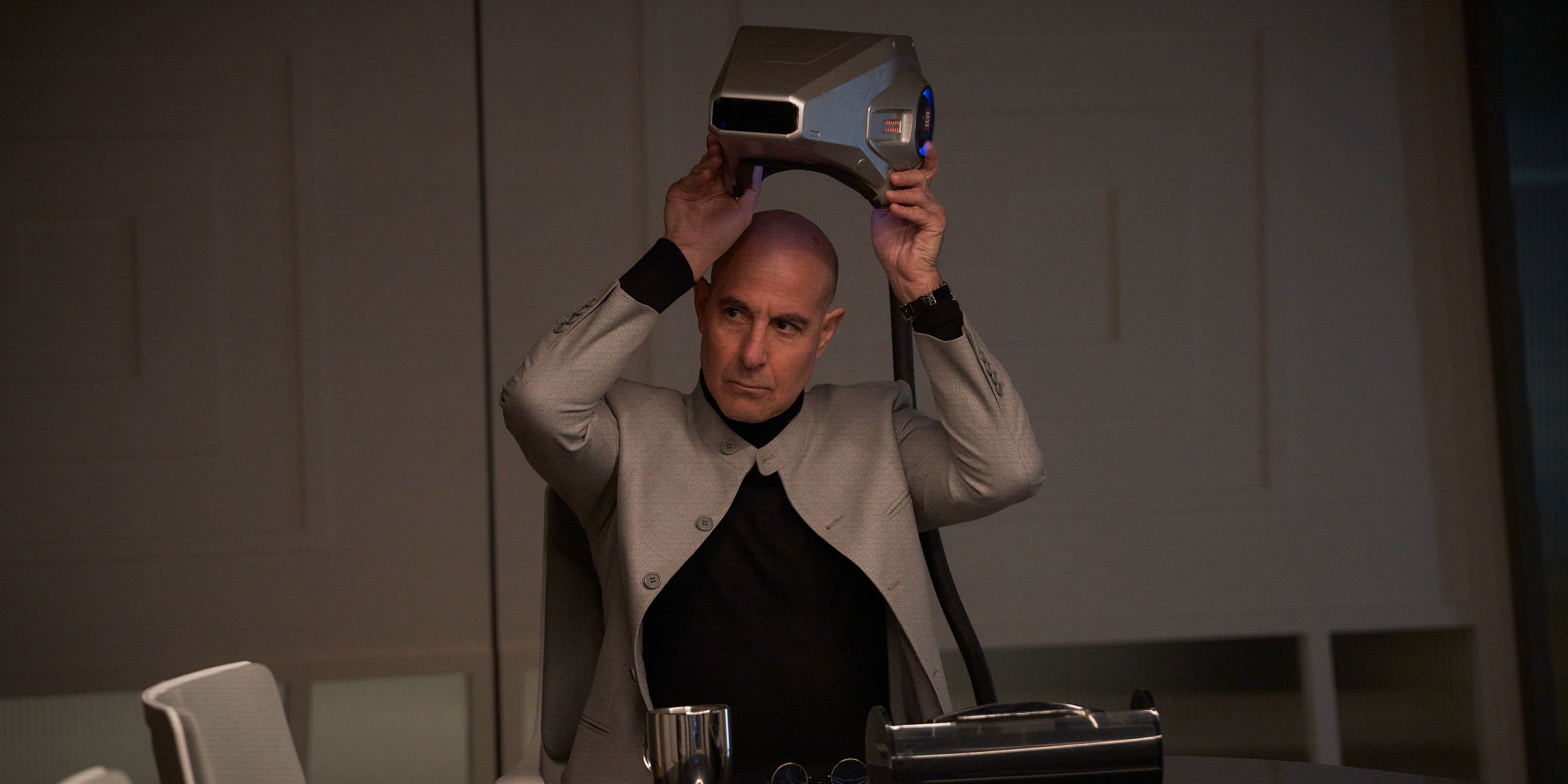 Stanley Tucci putting on a neurocaster helmet in The Electric State