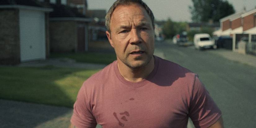 Stephen Graham as Eddie, standing in the street and looking concerned in Adolescence.