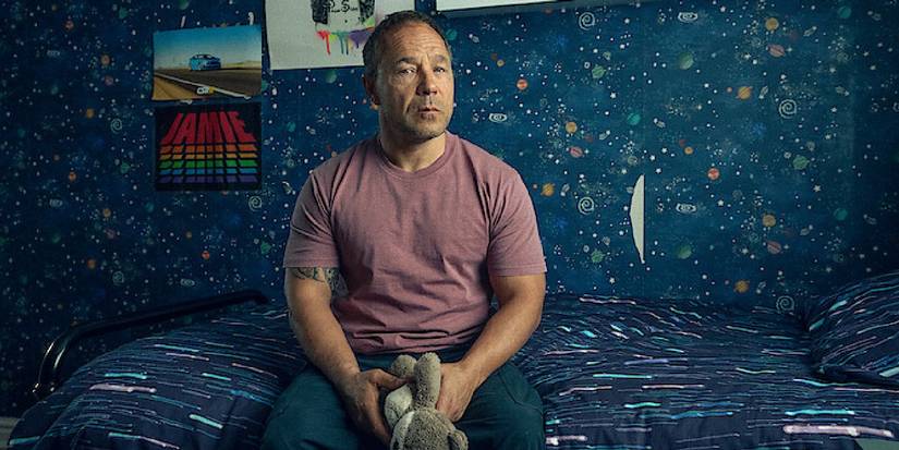 Stephen Graham as Eddie Miller sitting on Jamie's bed holding a stuffed toy in Adolescence.