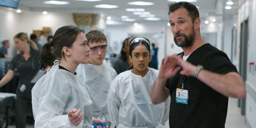 Dr. Robi (Noah Wyle) giving instructions to Dr. Trinity Santos, Dr. Dennis Whitaker, and Dr. Victoria Javadi in The Pitt Season 1 Ep 12