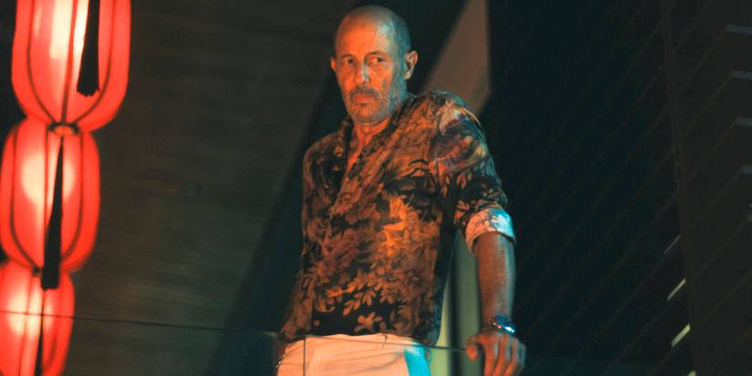 Greg/Gary (Jon Gries) watching from a balcony in The White Lotus Season 3 Ep 7