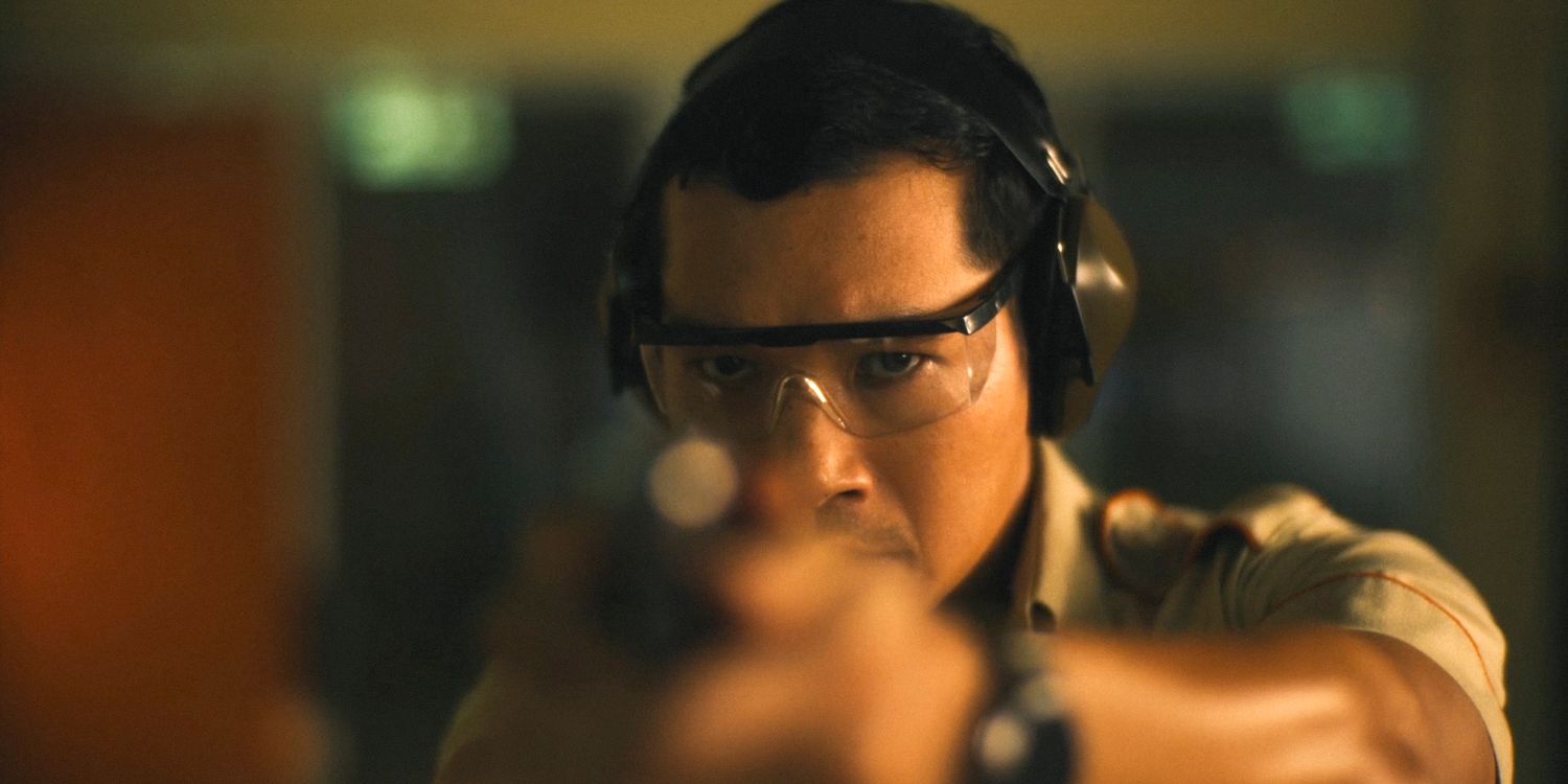 Gaitok (Tayme Thapthimthong) aiming a gun at the shooting range in The White Lotus Season 3 Episode 6