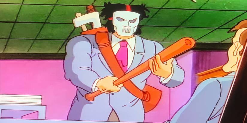 TMNT's Casey Jones wearing his hockey mask while wearing a suit in an office.