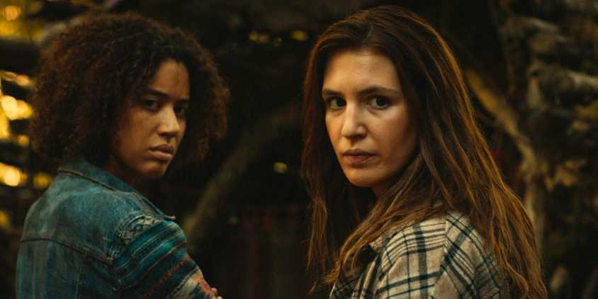 Teen Shauna (Sophie Nélisse) and Teen Taissa (Jasmin Savoy Brown) looking over their shoulders in Yellowjackets Season 3 Episode 8