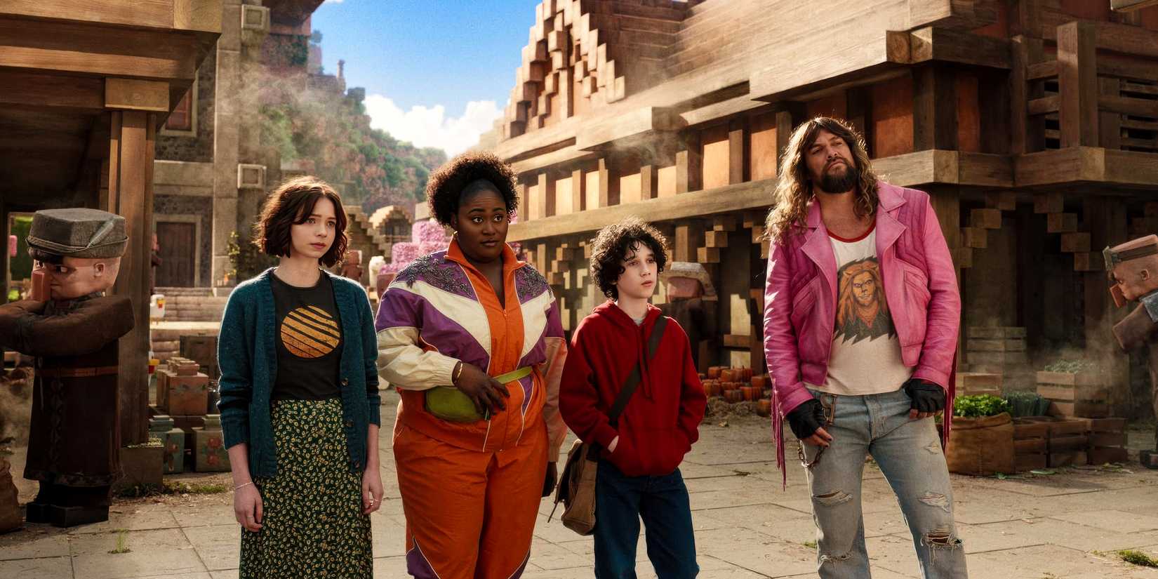 Garrett (Jason Momoa), Henry (Sebastian Hansen), Natalie (Emma Myers), and Dawn (Danielle Brooks) arriving at a village in A Minecraft Movie