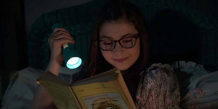 A young Amy with a flashlight reading a book in Young Sheldon