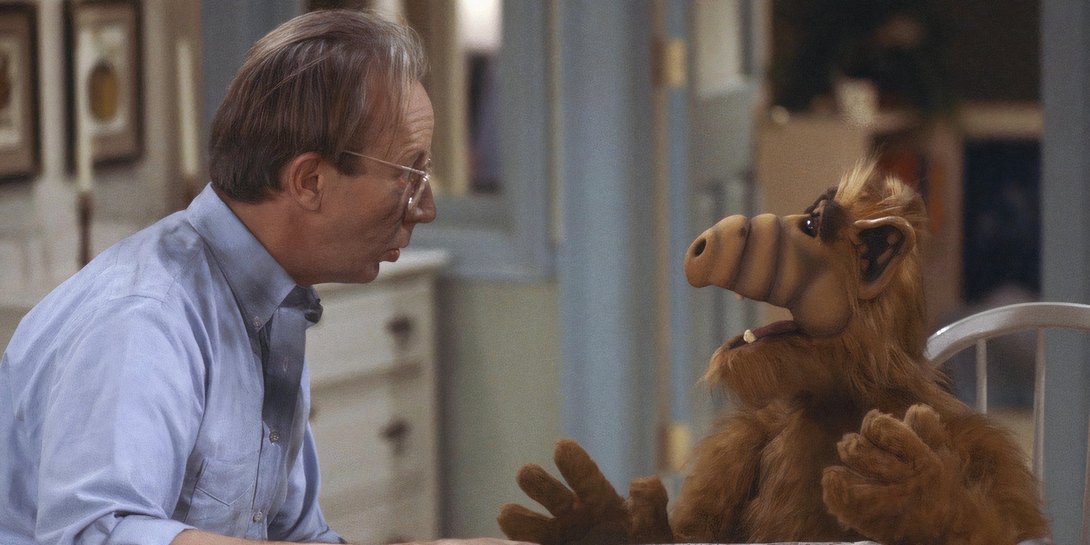 ALF speaks expressively to a man in glasses. 