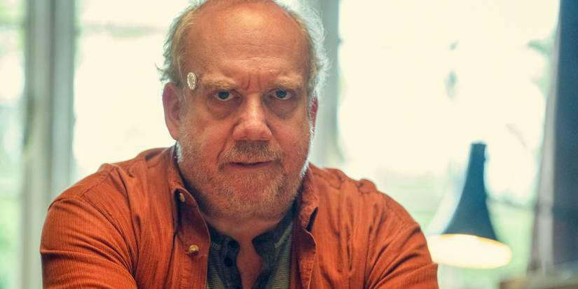 Phillip (Paul Giamatti) using a small device on his temple in Black Mirror Season 7 Ep 5