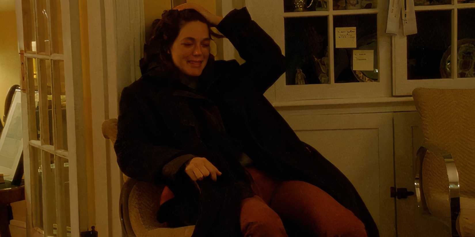 Callie Hernandez as Carrie crying while sitting in a chair in Invention