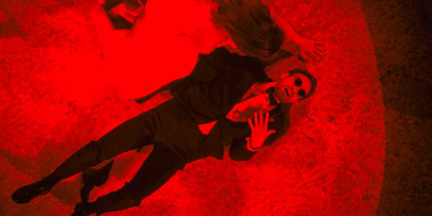 A scene in red, Matt Murdock (Charlie Cox) on the floor, wounded by a gunshot to the chest, and Heather worried in Daredevil: Born Again Season 1 Ep 8