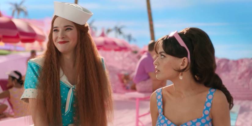 Doctor Barbie (Hari Nef) talking as Physicist Barbie (Emma Mackey) looks at her in Barbie.
