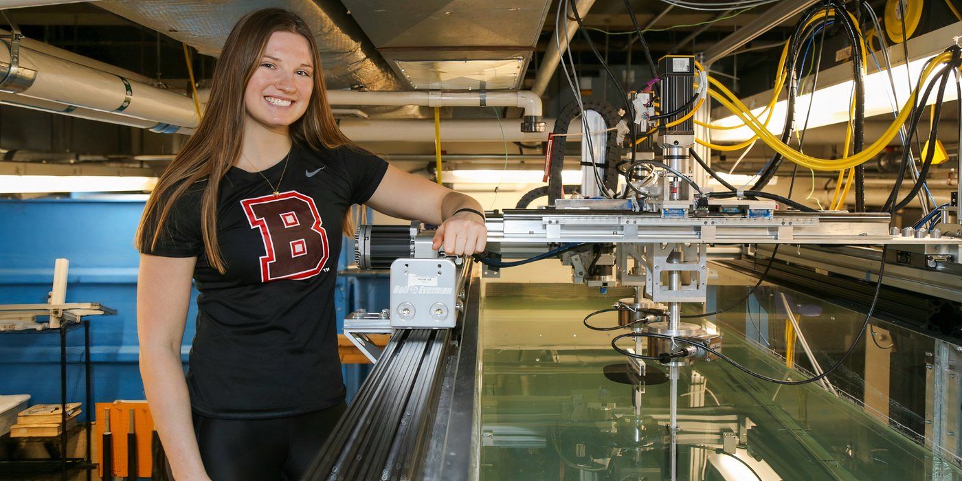 Eva Erickson from Survivor 48 wearing a Brown University t-shirt and operating a robotic tank.