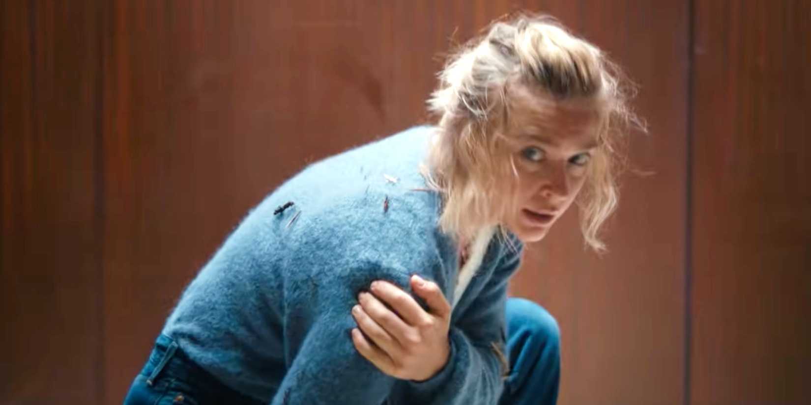 Sara in the elevator clutching her arm in Exterritorial 