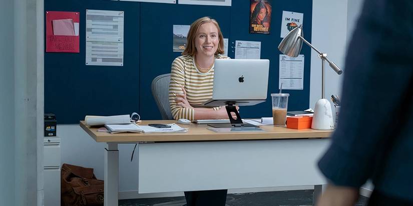 Hannah Einbinder as Ava who is sitting at her desk in Hacks