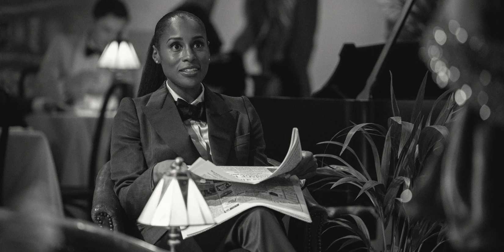 Brandy (Issa Rae) as Dr. Alex Palmer smiling and holding a newspaper in "Hotel Reverie"