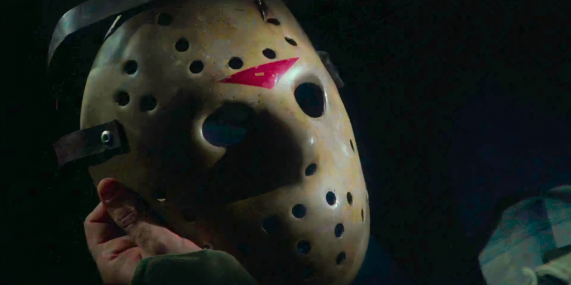 A close up of a hand holding Jason Voorhees&rsquo;s hockey mask