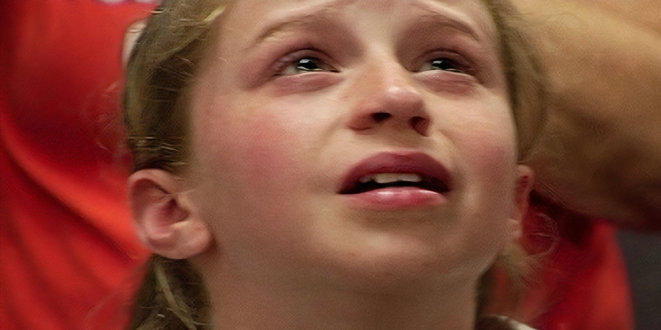 A young girl looks up at the ceiling with tears in her eyes. 