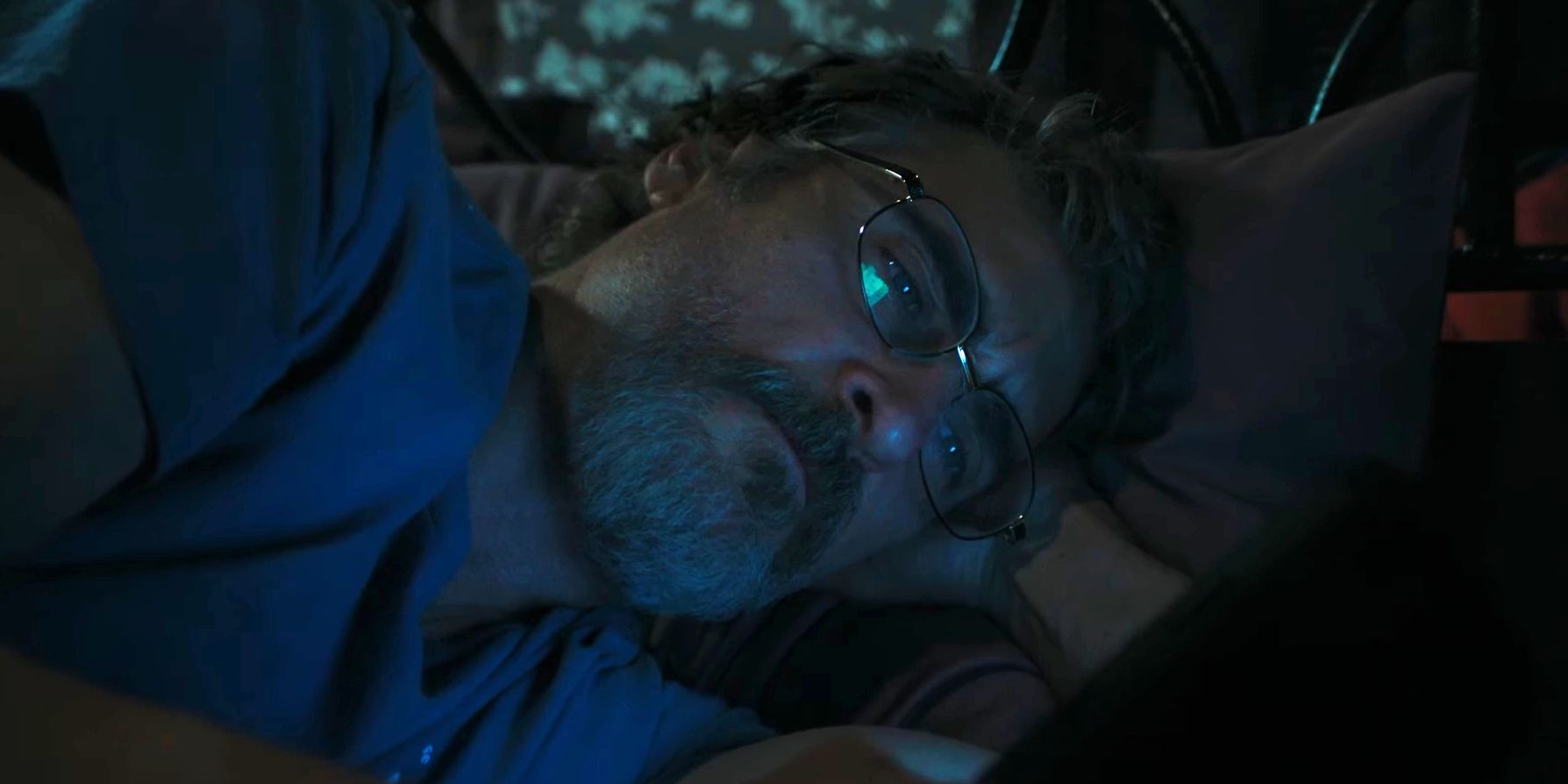 Joaquin Phoenix lying down and scrolling through his phone in Eddington