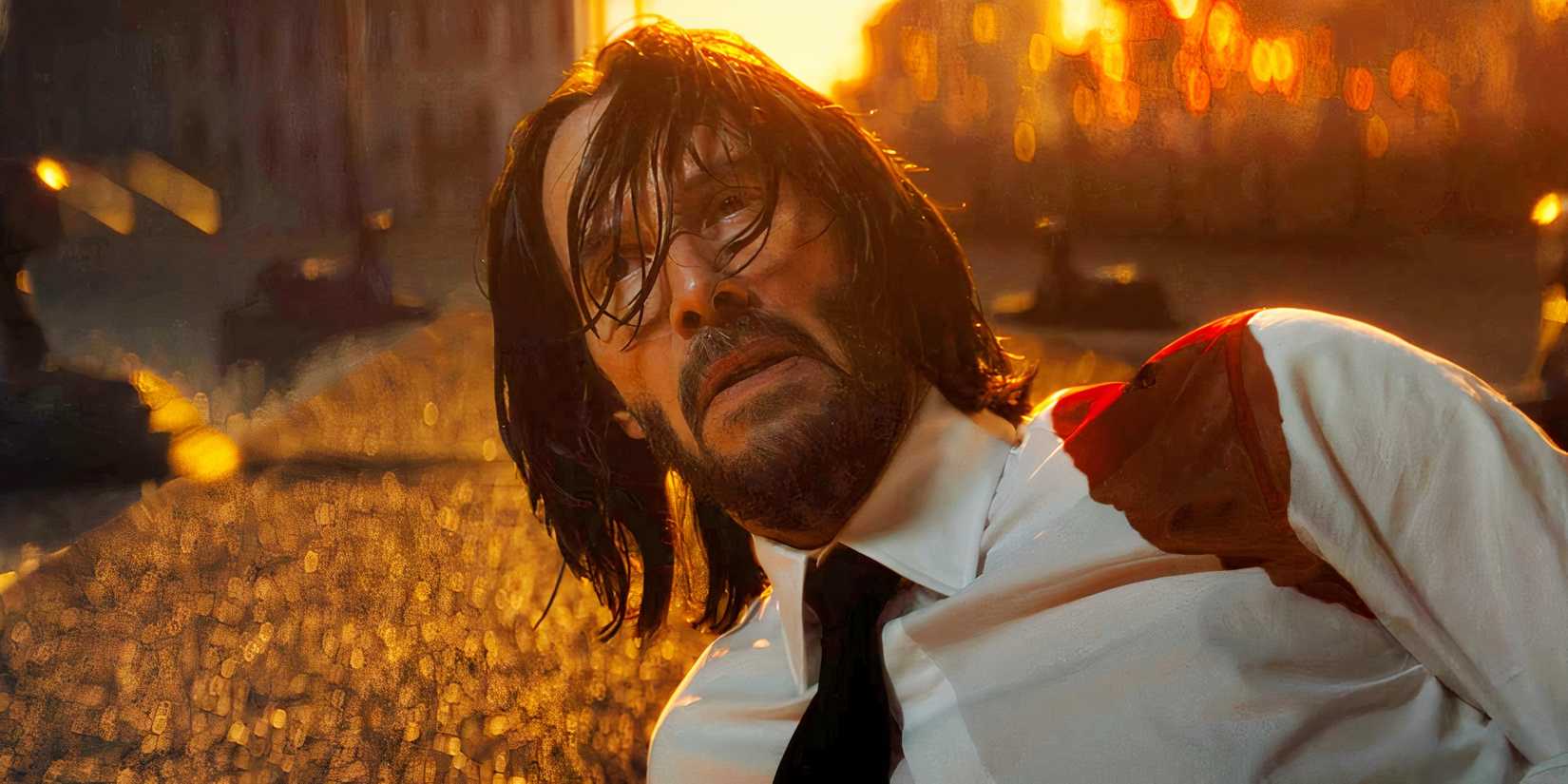 Keanu Reeves looking up from the ground with a bloody shoulder in John Wick: Chapter 4