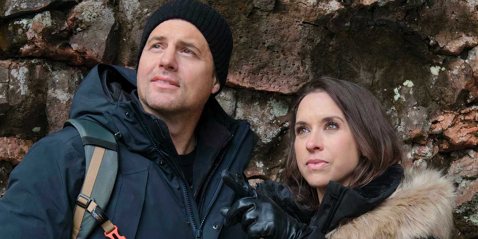 Kristoffer Polaha and Lacey Chabert in winter gear looking at something off screen in The Christmas Quest