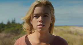 Milly Alcock as Simone looking in thought on beachside cliff in Sirens