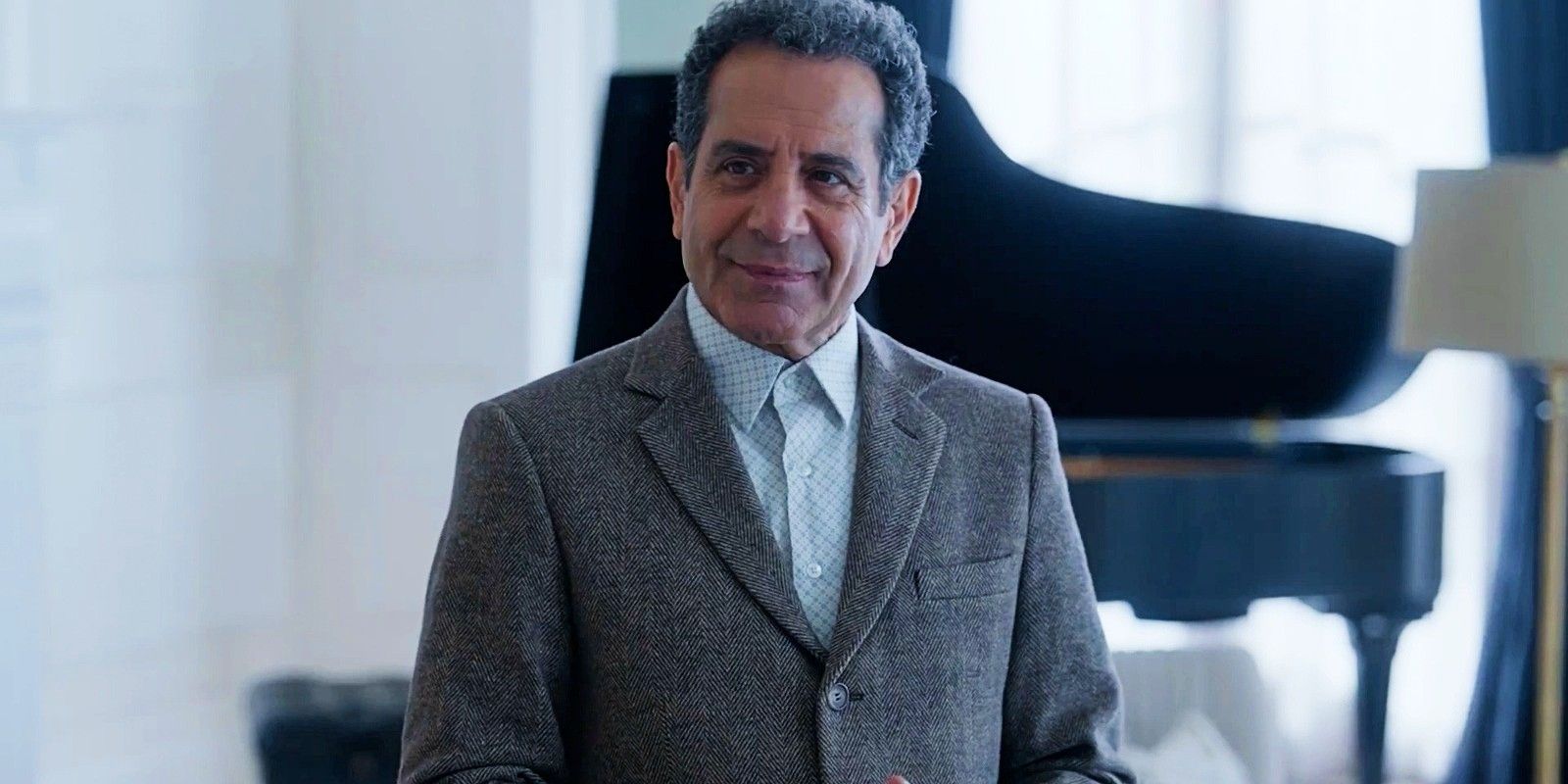 Adrian Monk (Tony Shalhoub) standing in front a piano and smiling in Mr. Monk&rsquo;s Last Case: A Monk Movie