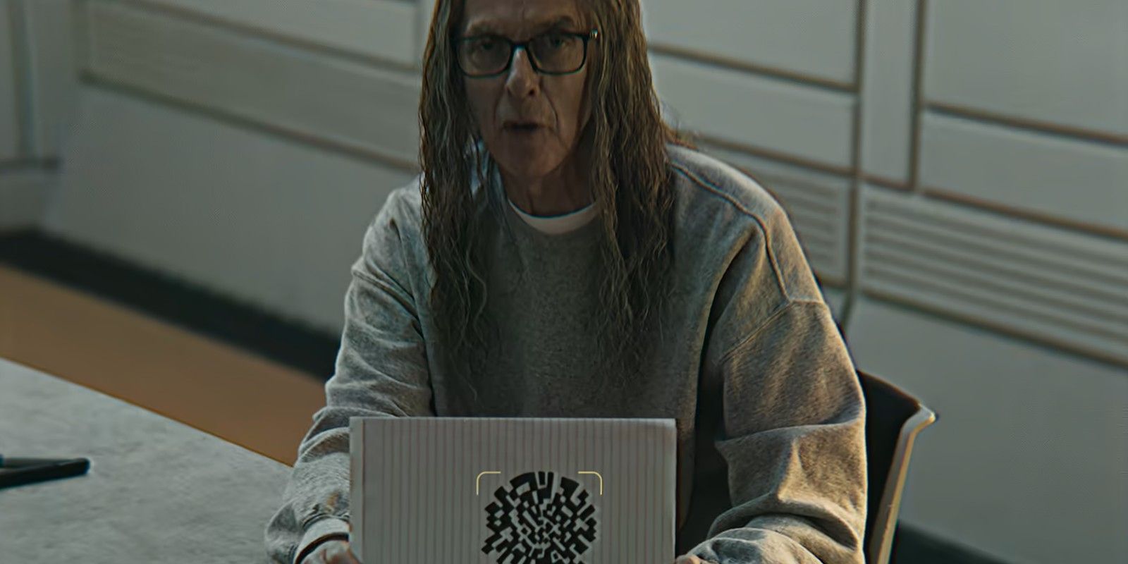 Older Cameron Walker (Peter Capaldi) holding up a code in Black Mirror season 7, episode 4, &ldquo;Plaything&rdquo;