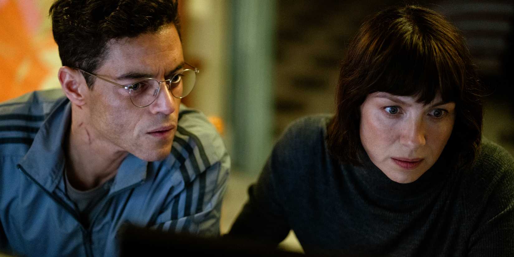 Rami Malek & Caitriona Balfe looking at a screen in The Amateur