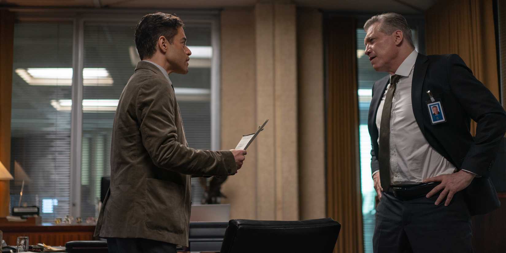 Rami Malek showing files to his boss in The Amateur