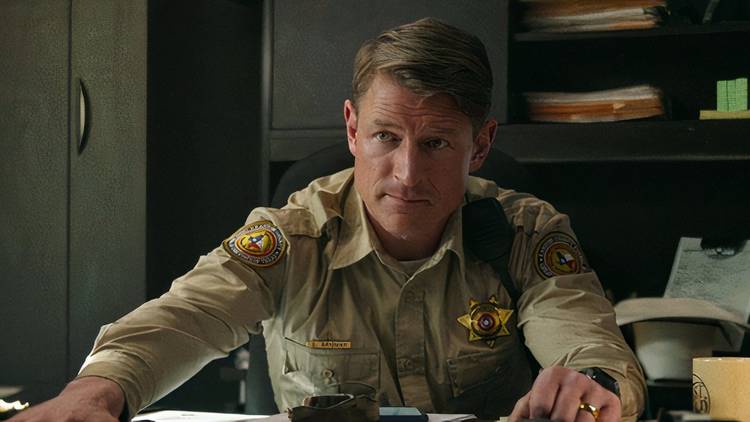 Sheriff Brigman sits behind his desk in Ransom Canyon season 1