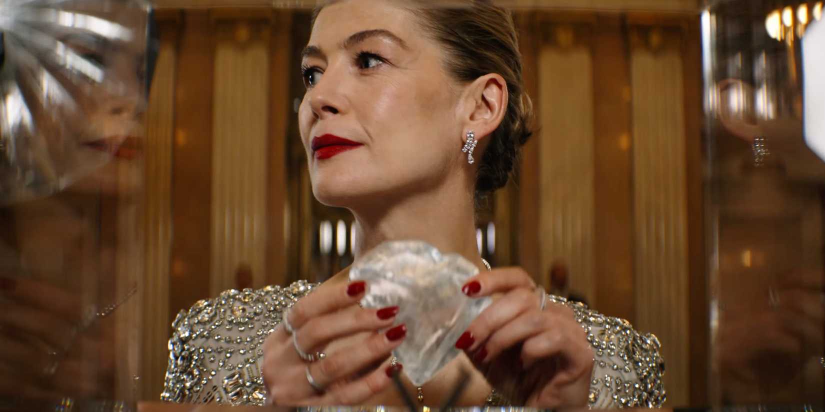 Rosamund Pike is touching a diamond in Now You See Me: Now You Don't 