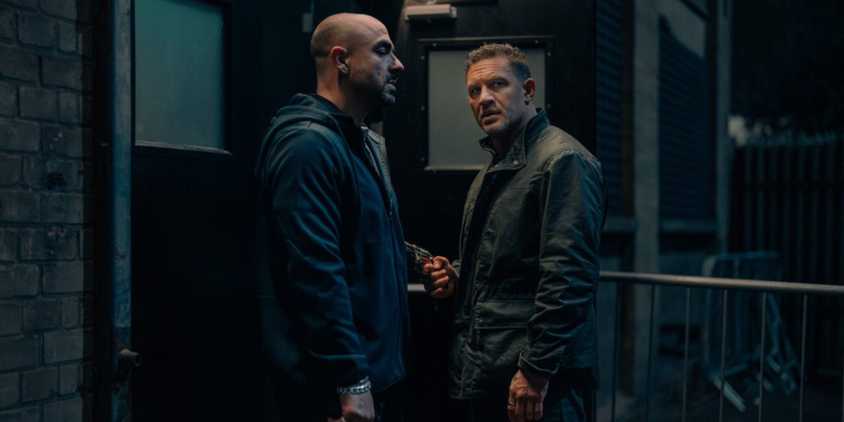 Tom Hardy as Harry Da Souza holds a gun to a bouncer in Mobland