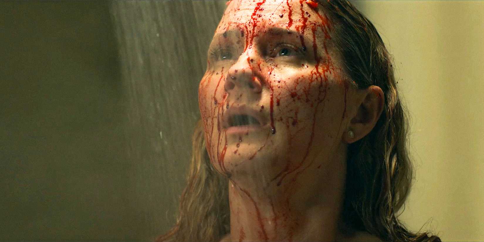 Maryanne (Jennifer Nettles) shocked, with her face splattered in blood, standing under the shower in The Bondsman Season 1