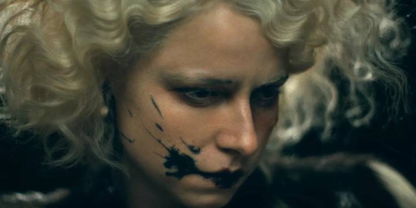 Jessie Buckley as the bride with something black splattered on her face in The Bride!