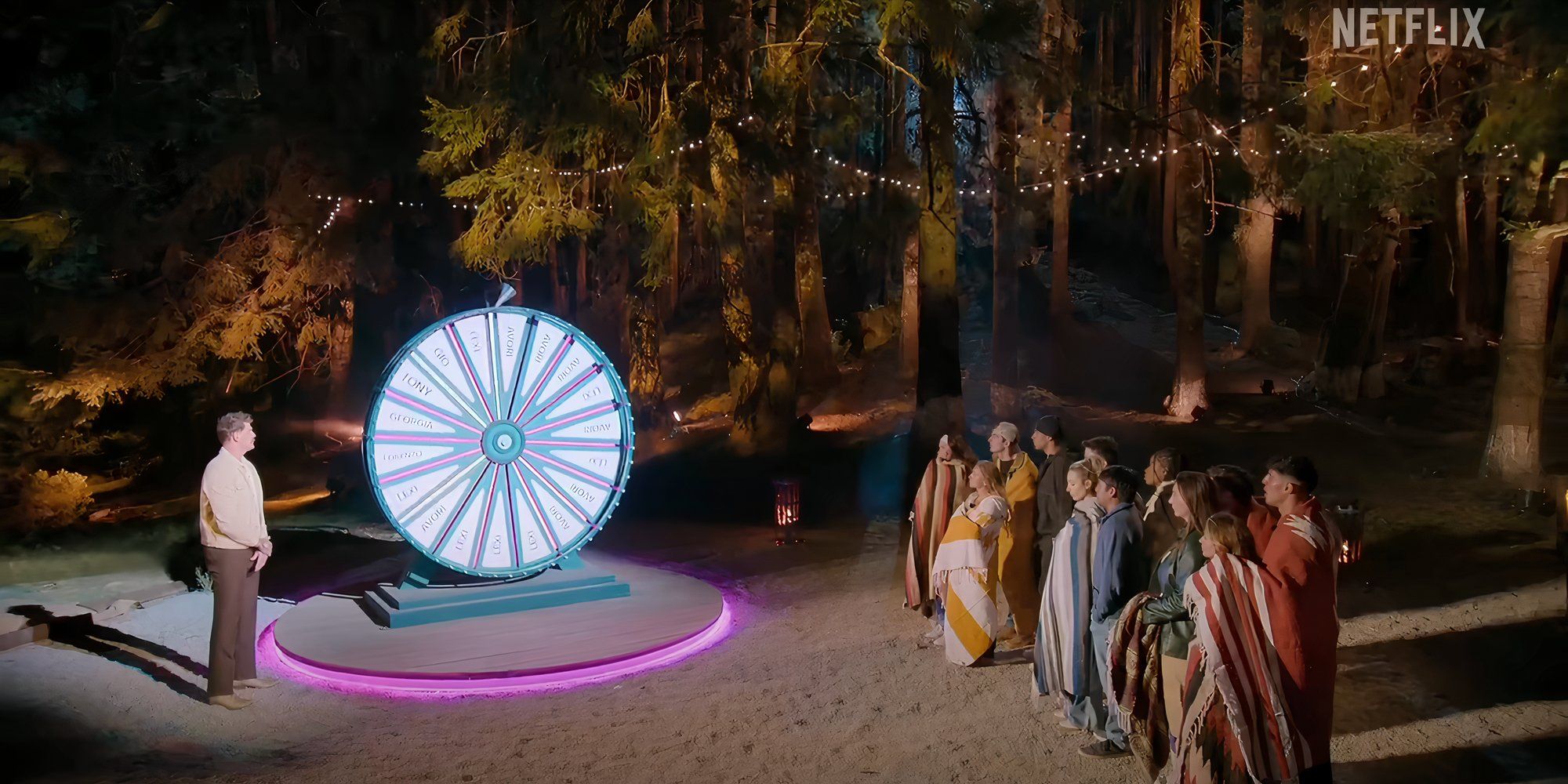 The cast gathers for elimination in the woods by the spinning wheel on Netflix&rsquo;s Battle Camp season 1