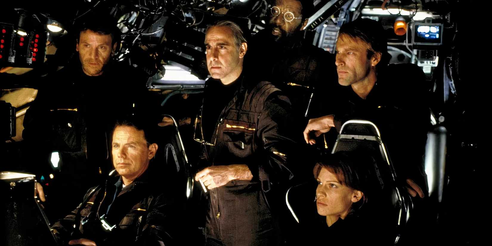 The cast of The Core inside a ship either standing or sitting