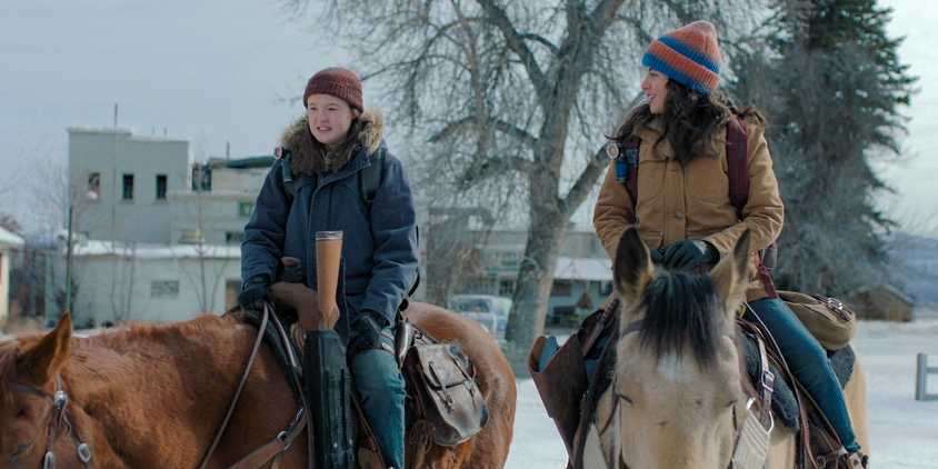 Ellie Williams (Bella Ramsey) and Dina (Isabela Merced) each riding their own horse in The Last of Us Season 2 Ep 1