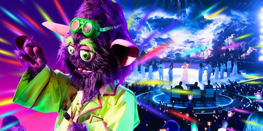 the masked singer star the mad scientist in close up with arm raised and show stage in background
