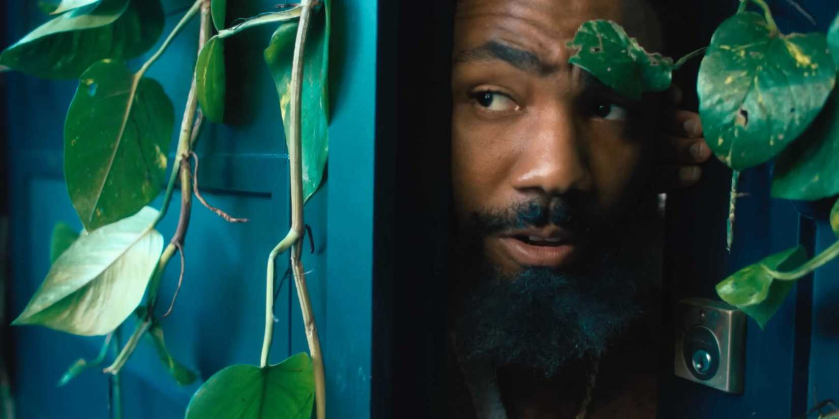 Danny Glover peeking out from a vine covered doorway in the Bando Stone trailer