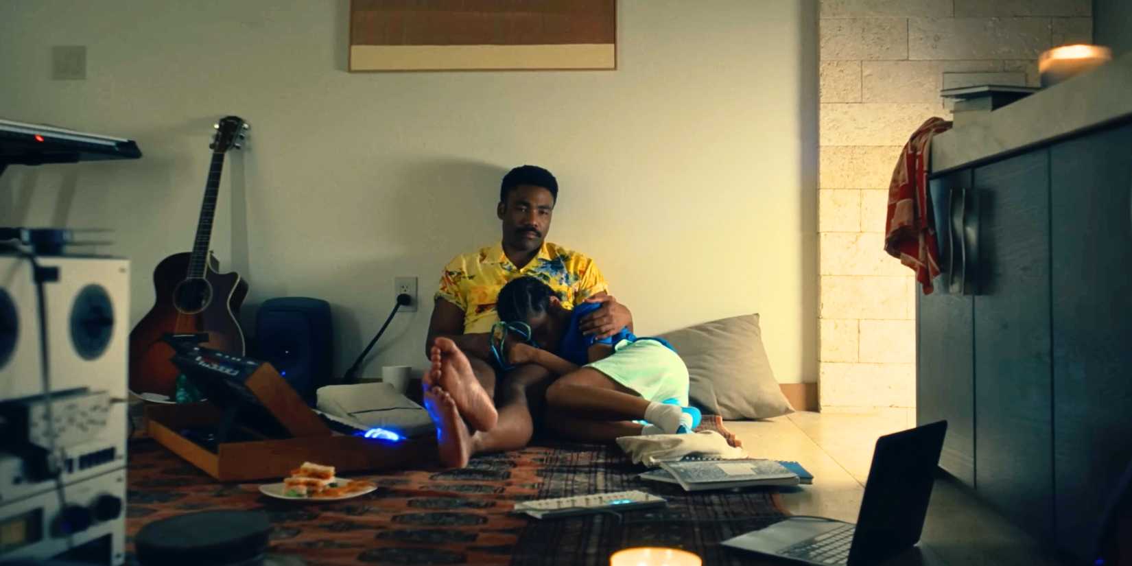 Donald Glover holding Legend while sitting on the floor in the Bando Stone trailer