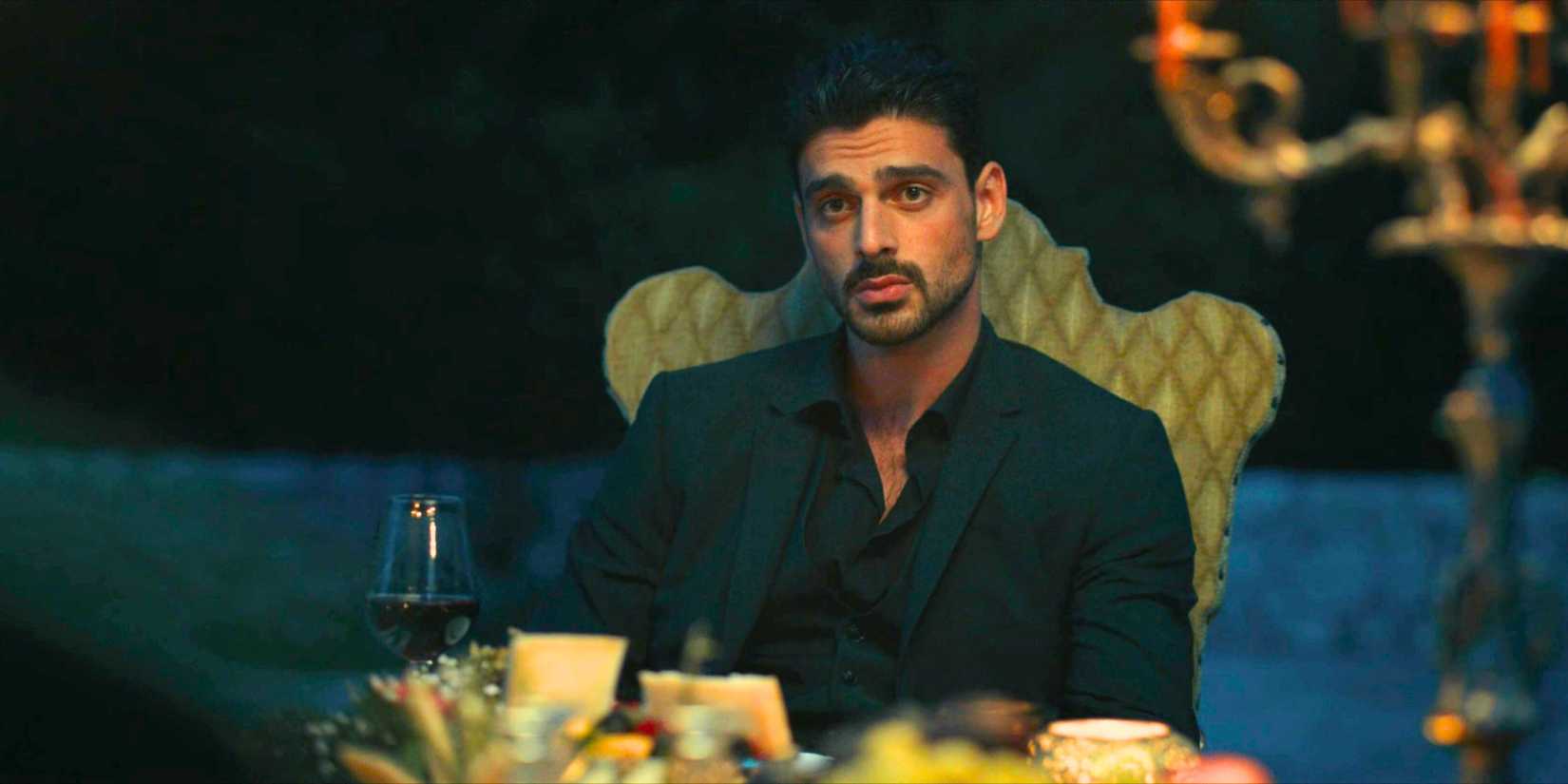 Michele Morrone sitting at a fancy dinner in 365 Days